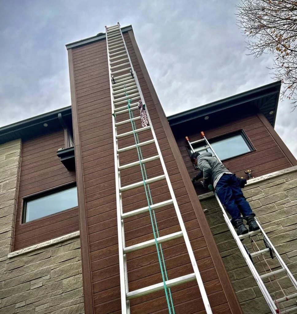 Technicien calfeutrant une fenêtre en hauteur sur un immeuble