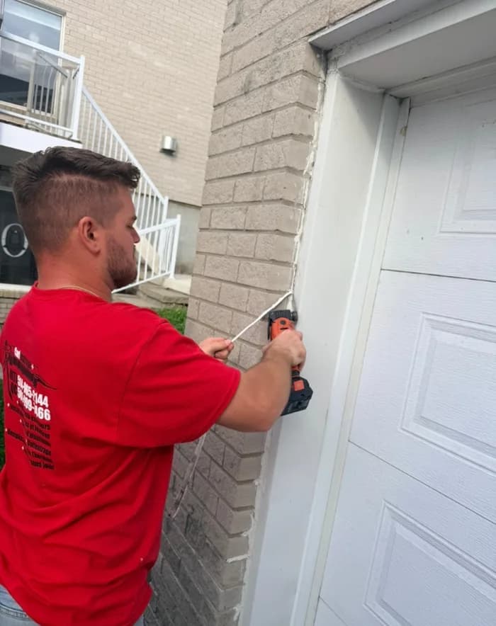 Technicien Carlfeutrage + calfeutrant le cadre d'une porte de garage