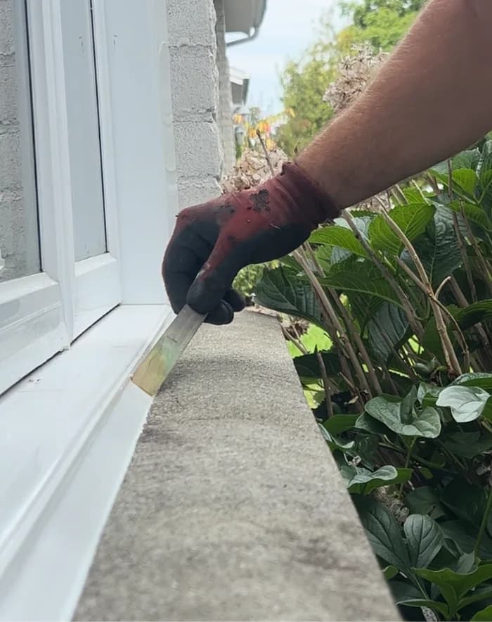Application de calfeutrant sur le rebord d'une fenêtre