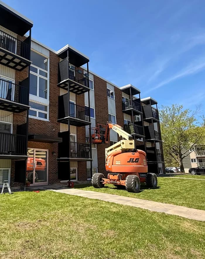 Nacelle ciseaux devant un immeuble de condos en rénovation